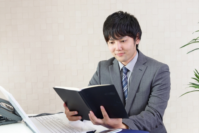 手帳をみて考える男性