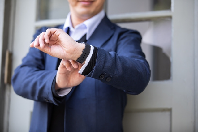腕時計で時間を確認する男性